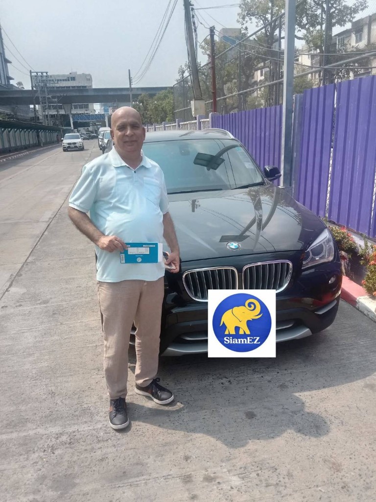 Customer with vehicle registration document next to a dark BMW SUV