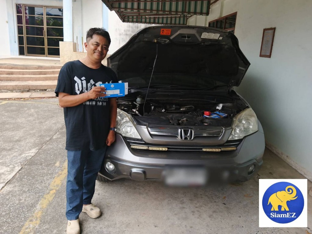 Customer holding vehicle registration document next to a gray Honda CR-V with hood open